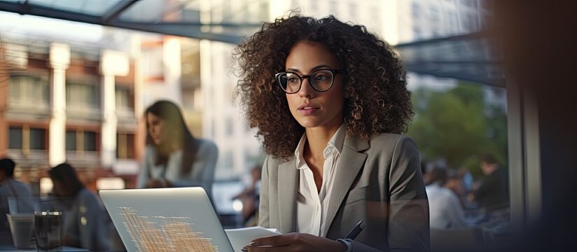 Beautiful confident curly business lady showing her financial and sales report on laptop pc for her focused high skilled multiracial business colleagues working on city district urban planning