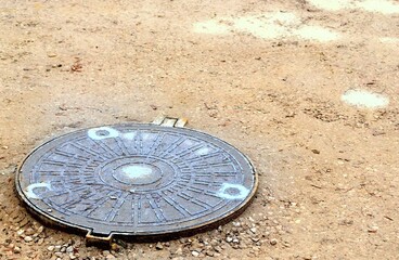 Sewer cover , a septic tank in a muddy road after rain in puddles