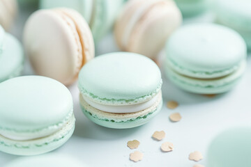 Obraz premium A close-up of pastel-colored macarons scattered on a surface, with tiny heart confetti adding to the charming setup.
