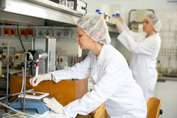 Young female scientist chemist concentratedly weighs the capsules on the scales in the laboratory