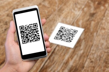 Human hand holding mobile phone with black qr code