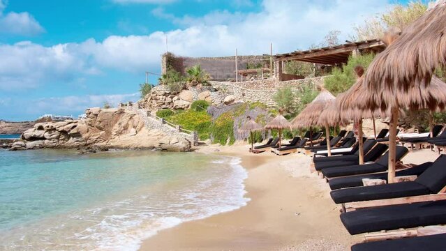 Paraside Beach in Mikonos, Greece, umbrella and luxury beach chairs beds in front of blue ocean. Most famous beach with crystal water and beach music bars. Gimbal cinematic ProRes graded from Log