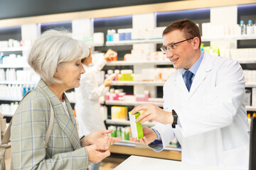 Elderly woman client consults with a pharmacist which medicinal ointment to buy