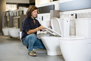 man in store chooses white toilet for new home. repair, arrangement of apartment and purchase of...