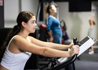 Sporty woman doing cardio workout out, training on exercise bike