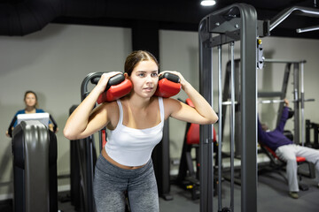 Fototapeta na wymiar Young woman is engaged on simulator to strengthen muscles of legs in the gym