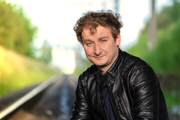 A middle-aged man against the background of the railroad tracks going away in the distance, perspective.