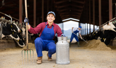 Young woman works on dairy farm with can in her hands
