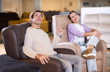 Obraz premium Man and woman sitting around in armchairs in furniture store