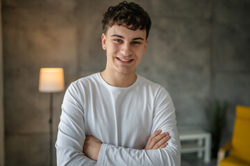 Portrait of one caucasian man 20 years old looking to the camera at home smiling wearing casual...
