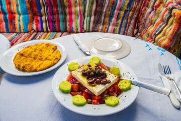 Greek salad plate and pita bread on table of typical tavern restaurant in Kimolos village, Kimolos island, Greece - 692233776