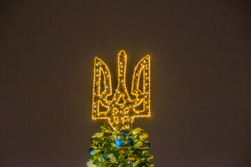 Christmas tree and lights at night in Kyiv. Coat of arms of Ukraine, New Year decoration. Decorated...