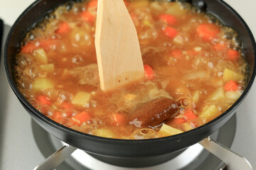 Close Up Cooking Japanese Curry Roux Soup in Black Pan