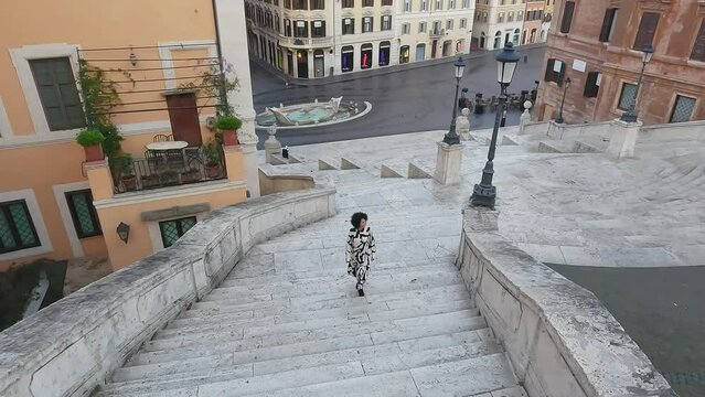 Fashion woman walking down the empty Spanish Steps in Rome, Italy in dawn morning, aerial drone cinematic shot