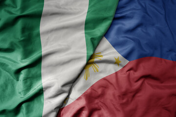 Obraz premium big waving national colorful flag of philippines and national flag of nigeria .
