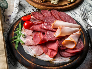 Antipasto cold meat platter with sausage, ham, salami,  parma, prosciutto, bacon decorated with cheese, vegetables on rustic wooden background with a glass of wine. Meat snacks, set of wine, top view