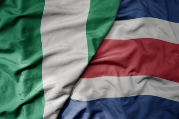 Fototapeta premium big waving national colorful flag of costa rica and national flag of nigeria .