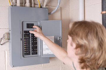 Shutting off power at the electrical service panel. Man shutting off main circuit breaker