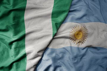 big waving national colorful flag of argentina and national flag of nigeria .
