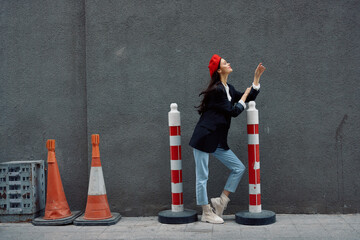 Fashion woman standing leaning against a wall street against a background of the city road works...