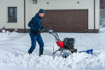 A man is shoveling snow during snowy weather in winter. Right view