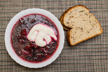 Borscht - sour soup common in Eastern Europe - made with red beetroots and sour cream - piece of bread
