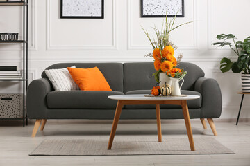 Beautiful autumn bouquets and pumpkins on coffee table near sofa in room