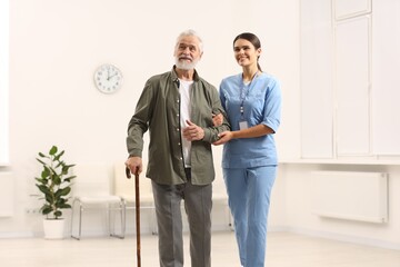 Smiling nurse supporting elderly patient in hospital
