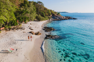 Koh Samet Island Thailand, aerial drone view from above at a couple of men and woman walking on the beach of Samed Island in Thailand with a turqouse colored ocean and a white tropical beach © Fokke Baarssen