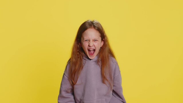 Irritated angry preteen child girl kid scream from stress tension problems feels horror hopelessness fear surprise shock expresses rage nervous quarrel. Teenager children isolated on yellow background