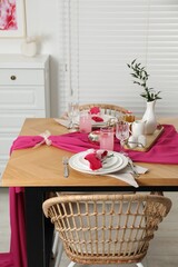 Color accent table setting. Glasses, plates, pink napkins and vase with green branch in dining room