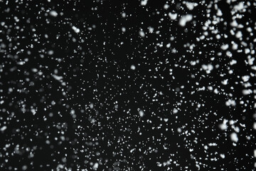 Obraz premium White snow falling down on black background