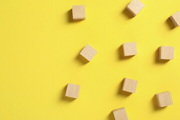 Fototapeta na wymiar Blank wooden cubes on yellow background, flat lay. Space for text