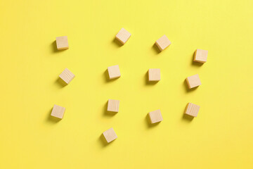 Fototapeta na wymiar Blank wooden cubes on yellow background, flat lay