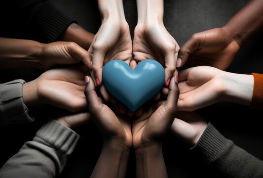 Hands of a team of people hold a heart. Background with selective focus and copy space