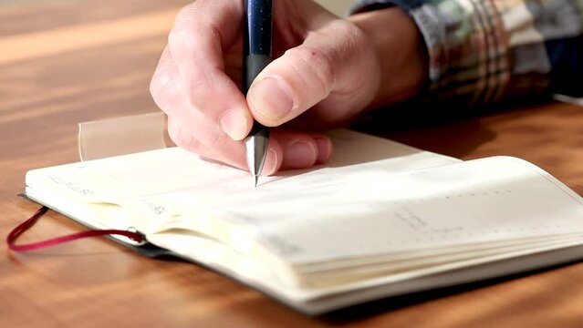 手帳に予定を書き込む男性