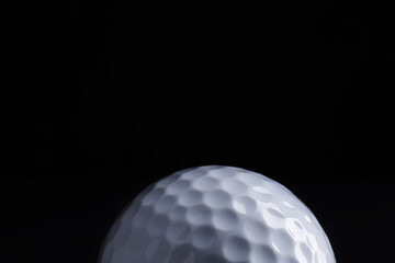 Golf ball on black background, closeup. Space for text
