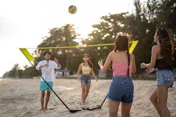 Group of Asian young men and women playing beach volley on the beach. 