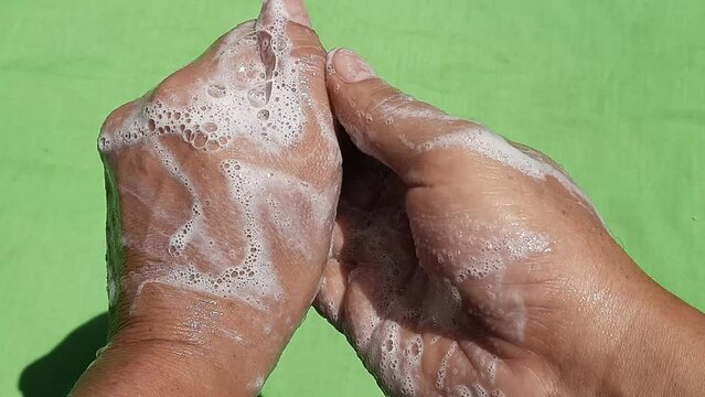 Wash your hands with green scented soap. cleaning body parts on green background