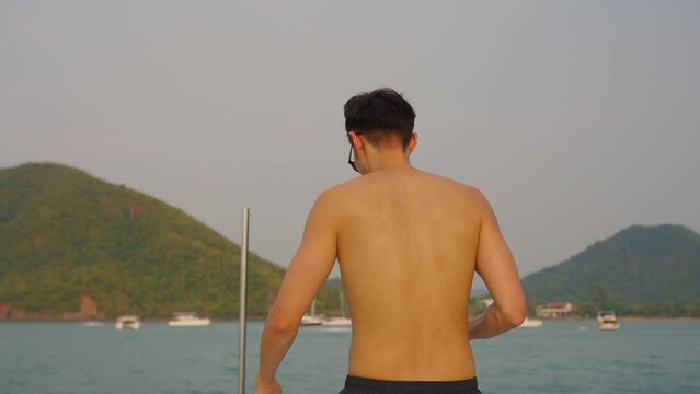 Asian young man tourist using smartphone taking photo during yachting. 
