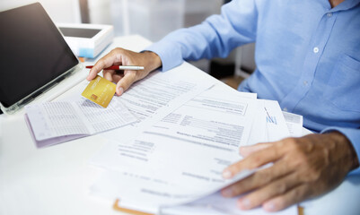 Accountant using tablet computer work on desk holding credit card and checking savings book, bank...