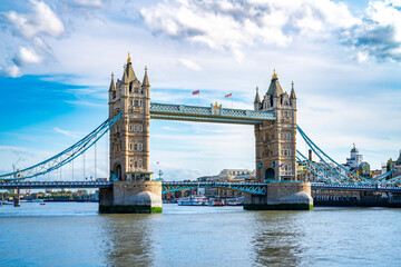 Amazing view of Tower bridge with flags over rippling river against cloudy blue sky in London