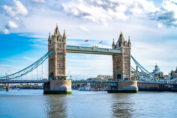 Deurstickers Amazing view of Tower bridge with flags over rippling river against cloudy blue sky in London © Itza