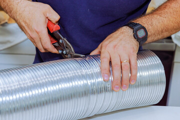 Man used scissors to cutting flexible aluminum corrugated pipe for vent air duct