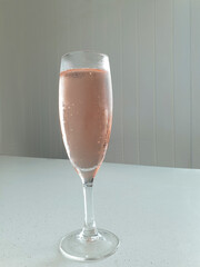 glass of sparkling rose wine in flute wine glass with space for text