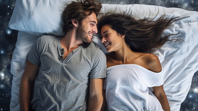Image of a young couple smiling and cuddling on comfortable bedding.