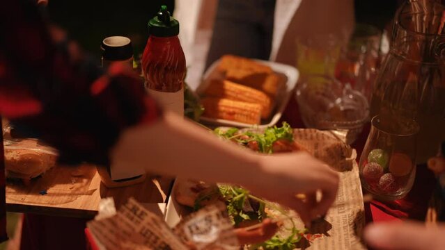 Forming ready-to-eat hot dogs on the table during an outdoor party with friends. Party food concept
