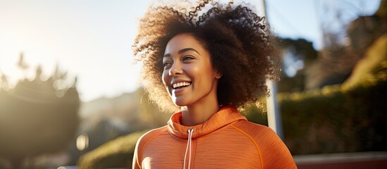 Content and upbeat African American woman enjoying a rejuvenating outdoor workout, smiling and taking a pause from running, inhaling the fresh air. - Powered by Adobe