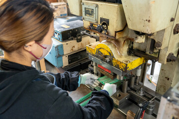 工場で機械を使い、働く女性