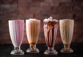 Assorted shakes of banana, strawberry, cream and chocolate served in glass isolated on wooden table side view of arabic drink
